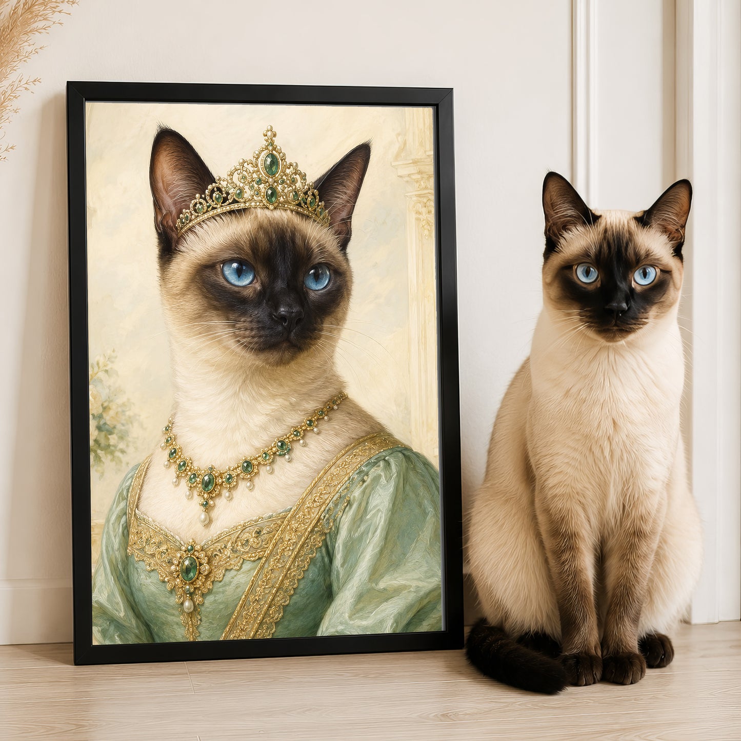 A Siamese cat wearing a green dress and a gold crown is standing next to a framed image of the same cat in a regal pose.