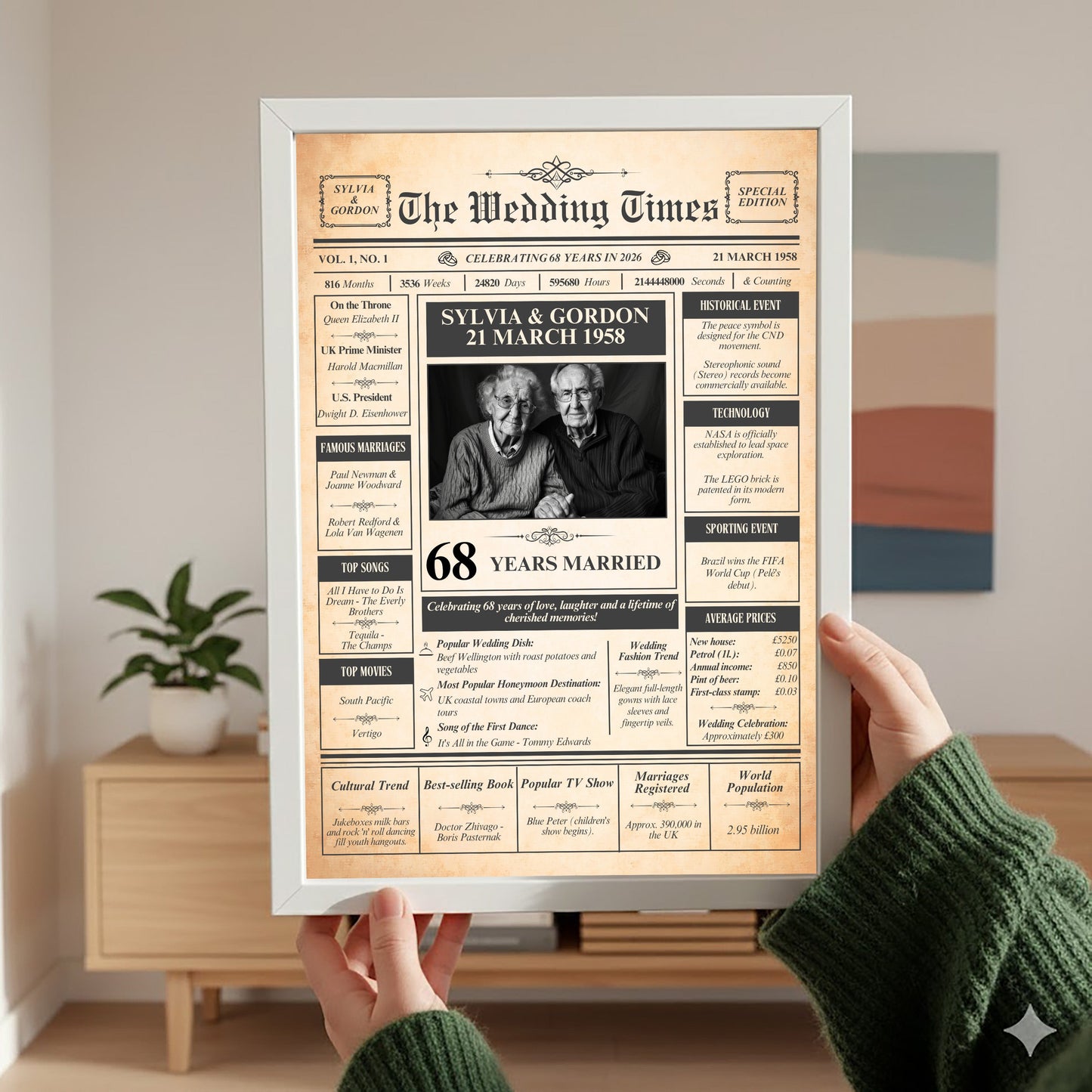 A person is holding up a framed newspaper-style birthday announcement for Sylvia Gordon, celebrating their 68th wedding anniversary.