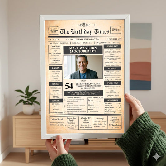 a person holding up a framed newspaper-style birthday announcement for a man named Mark, which includes his age, name, birth date, and various personal details.