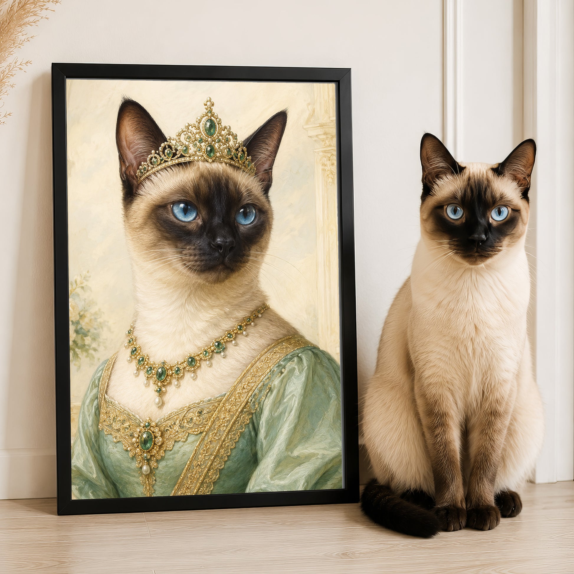 A Siamese cat wearing a green dress and a gold crown is standing next to a framed image of the same cat in a regal pose.